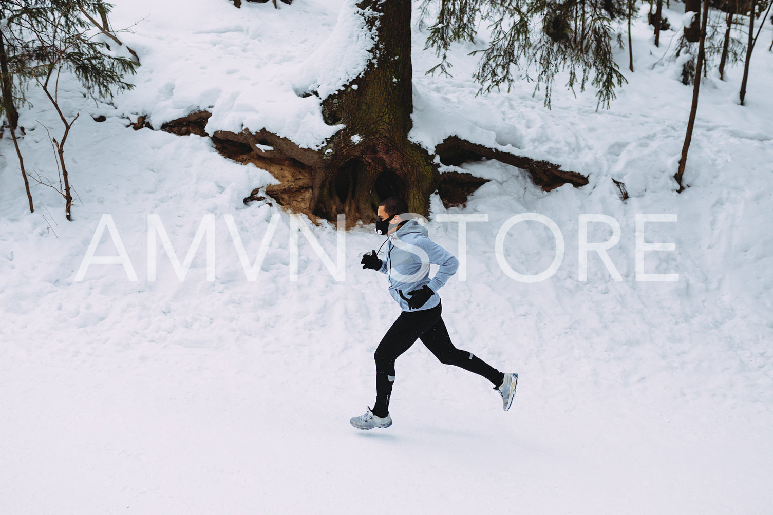 Side view of young athlete running through a park, wearing training mask	
