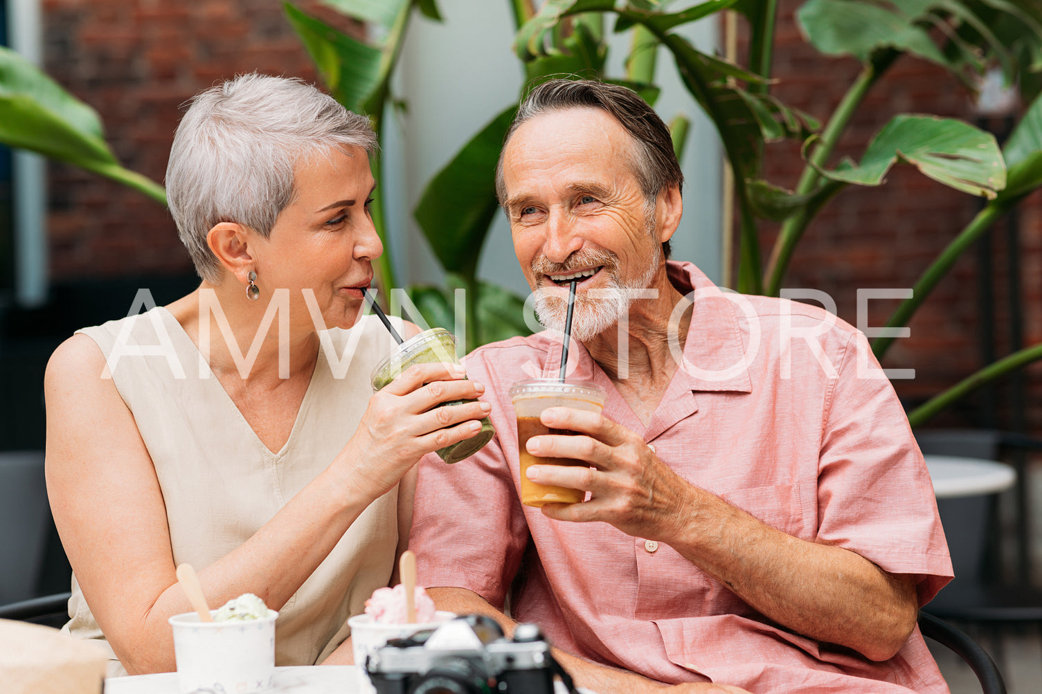 Happy aged couple drinking cocktails in an outdoor cafe. Smiling mature couple enjoying drinks outdoors.