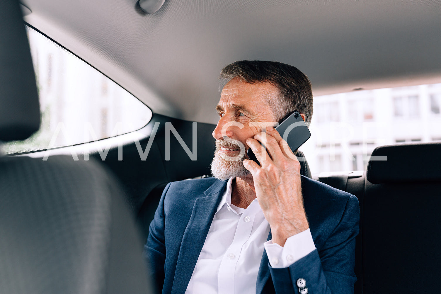 Mature businessman sitting on the backseat in the car. Senior man talking on the cell phone in a taxi.	