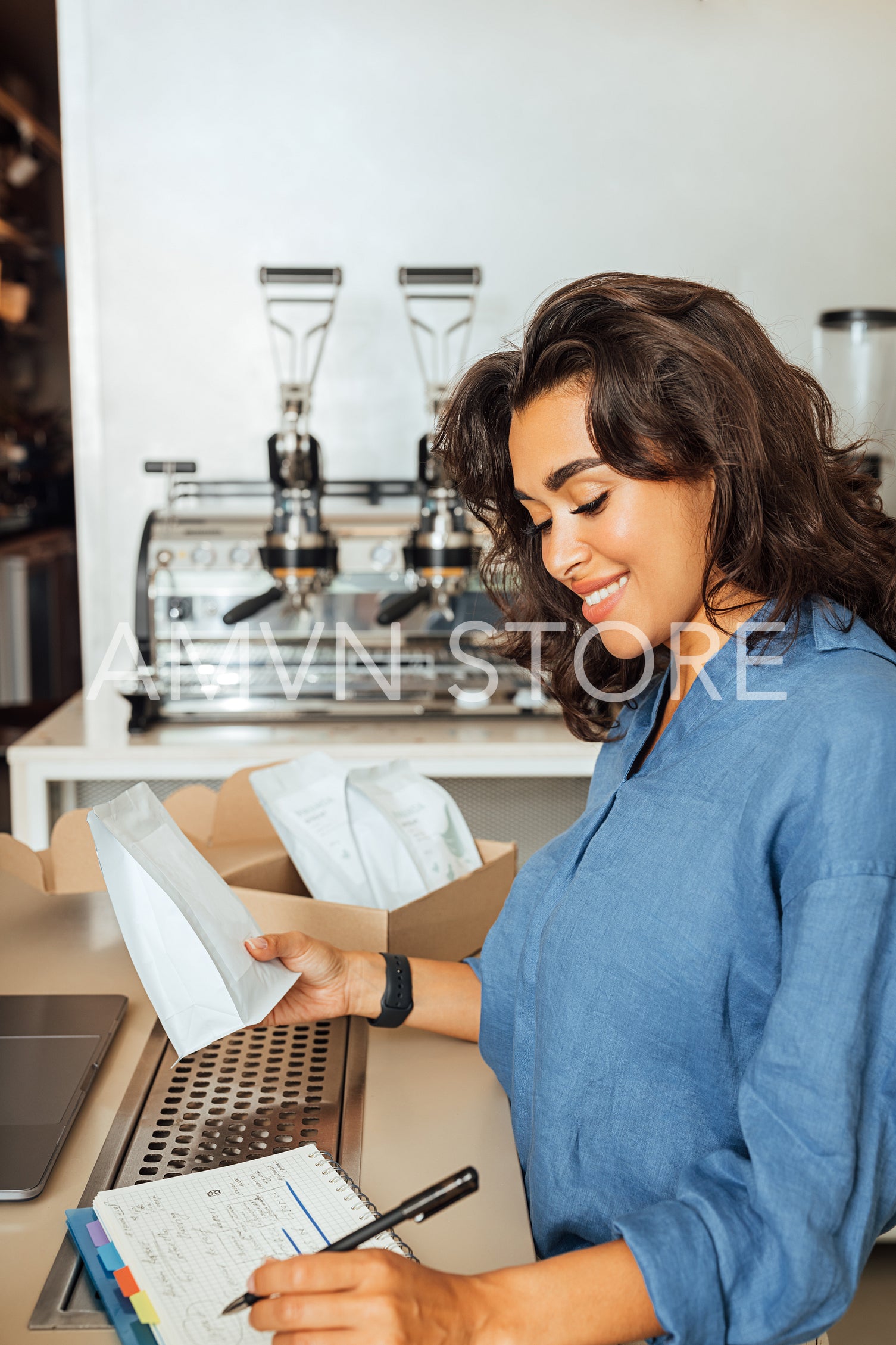 Middle east businesswoman holding a pack of coffee and writing in her cafeteria	