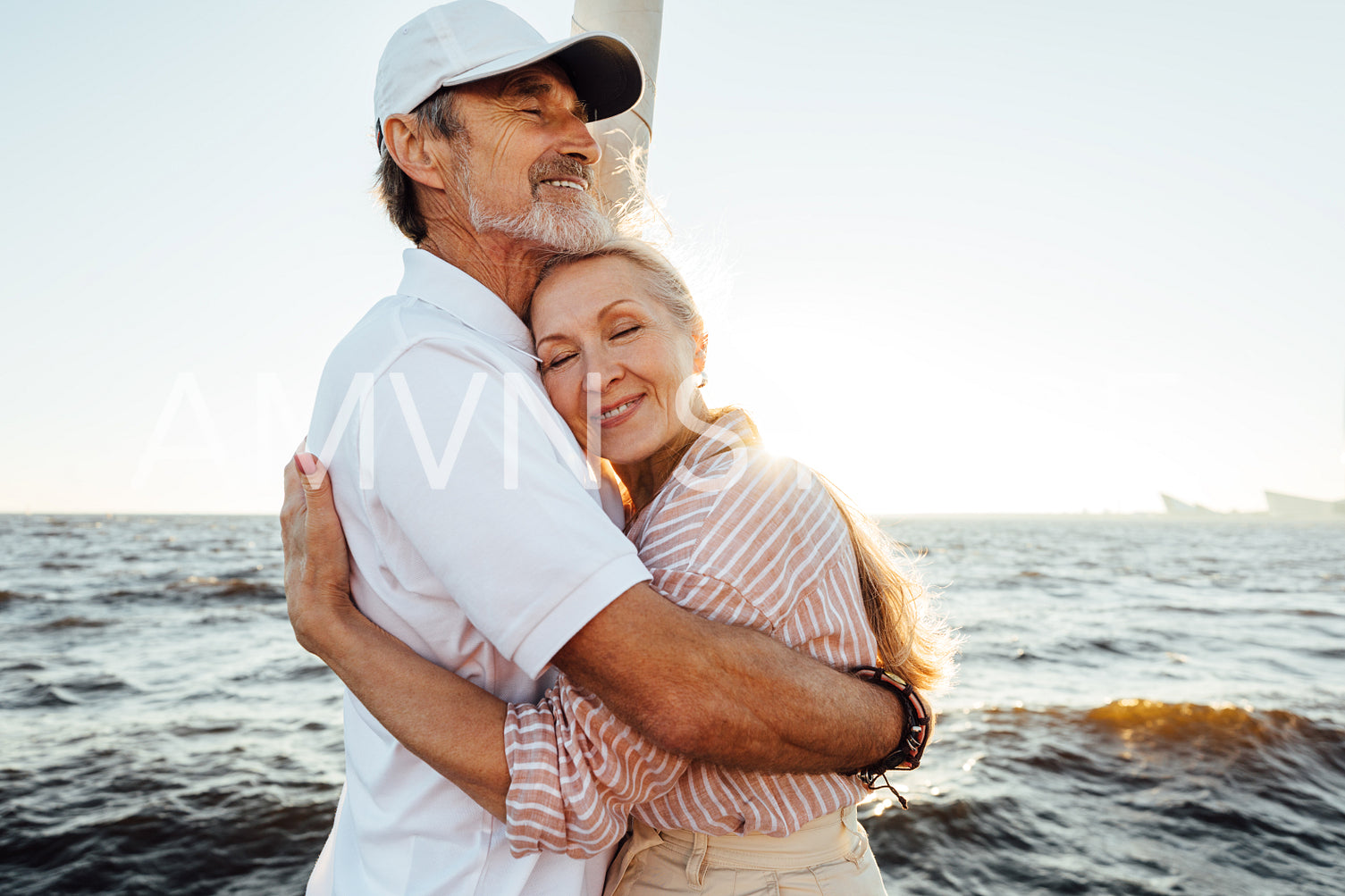 Affectionate senior couple embracing on private yacht. Beautiful mature woman leaning on husband's chest with eyes closed.	