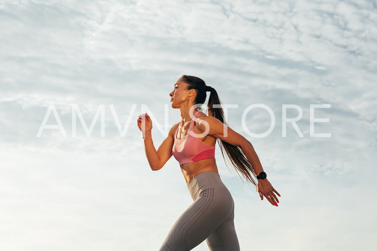 Sportswoman with long hair running outdoors against skies. Slim female jogger running on the rooftop.