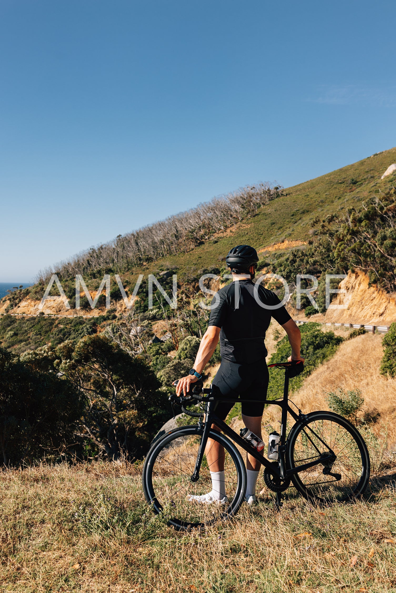 Professional cyclist in black sportswear leaning his bike looking at the view