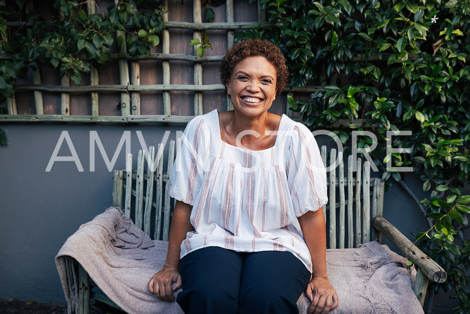 Happy mature woman on a bench. Smiling woman with short hair relaxing in backyard.