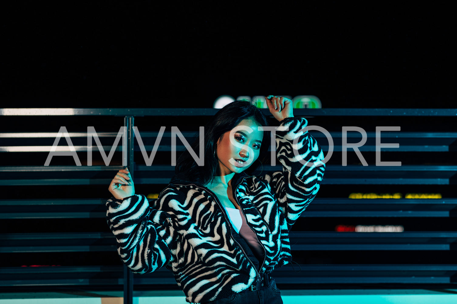 Young woman posing on a roof in front of a city lights and looking at camera	