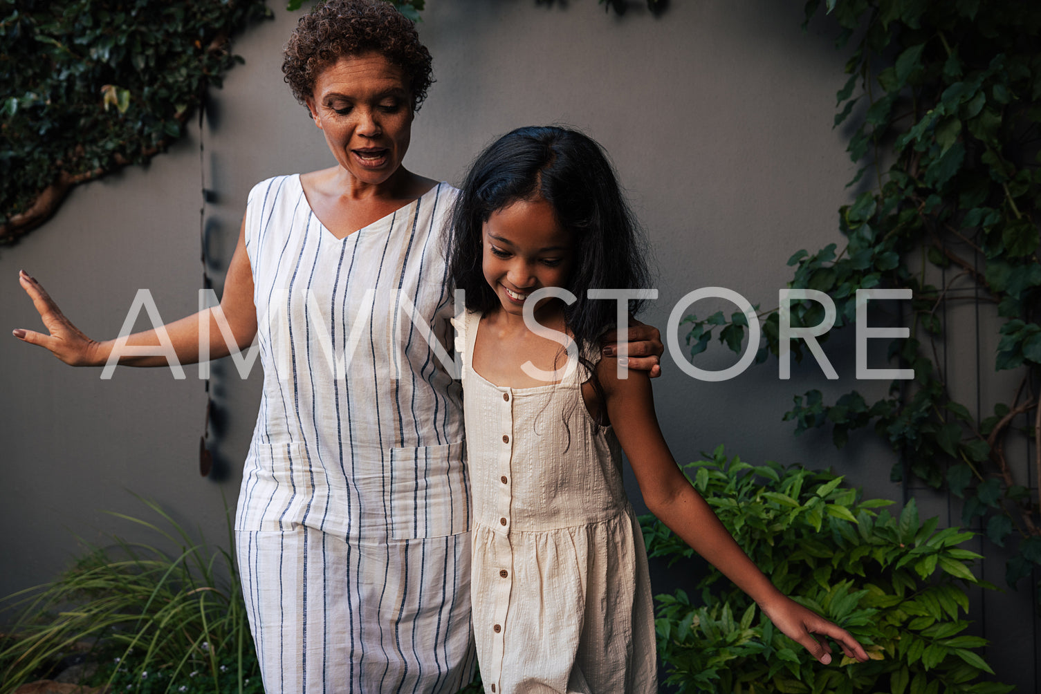 Happy grandma and granddaughter dancing together in backyard