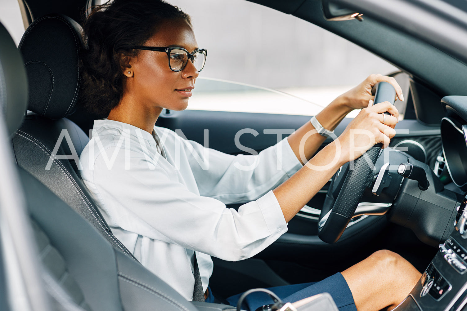 Woman driving a car. Side view of a female driver wearing glasses and looking away.	