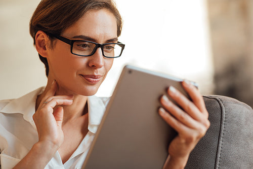 Close-up of a businesswoman in eyeglasses using a digital tablet. Portrait of a female with a digital tablet.