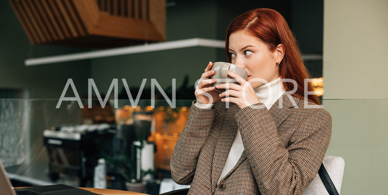 Woman in blazer drinking coffee at coffee shop