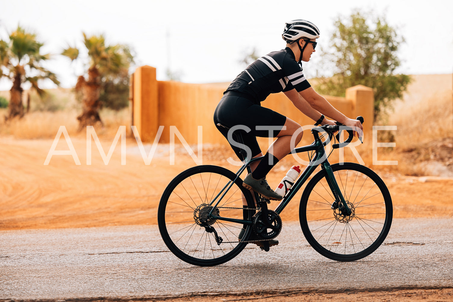 Side view of female cyclist riding bicycle on countryside road. Caucasian triathlete training for competition.