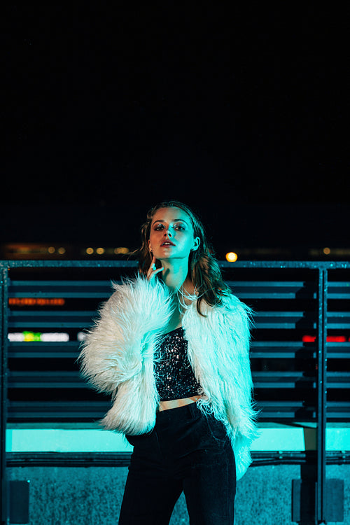 Young beautiful woman wearing white fur coat standing outdoors at night