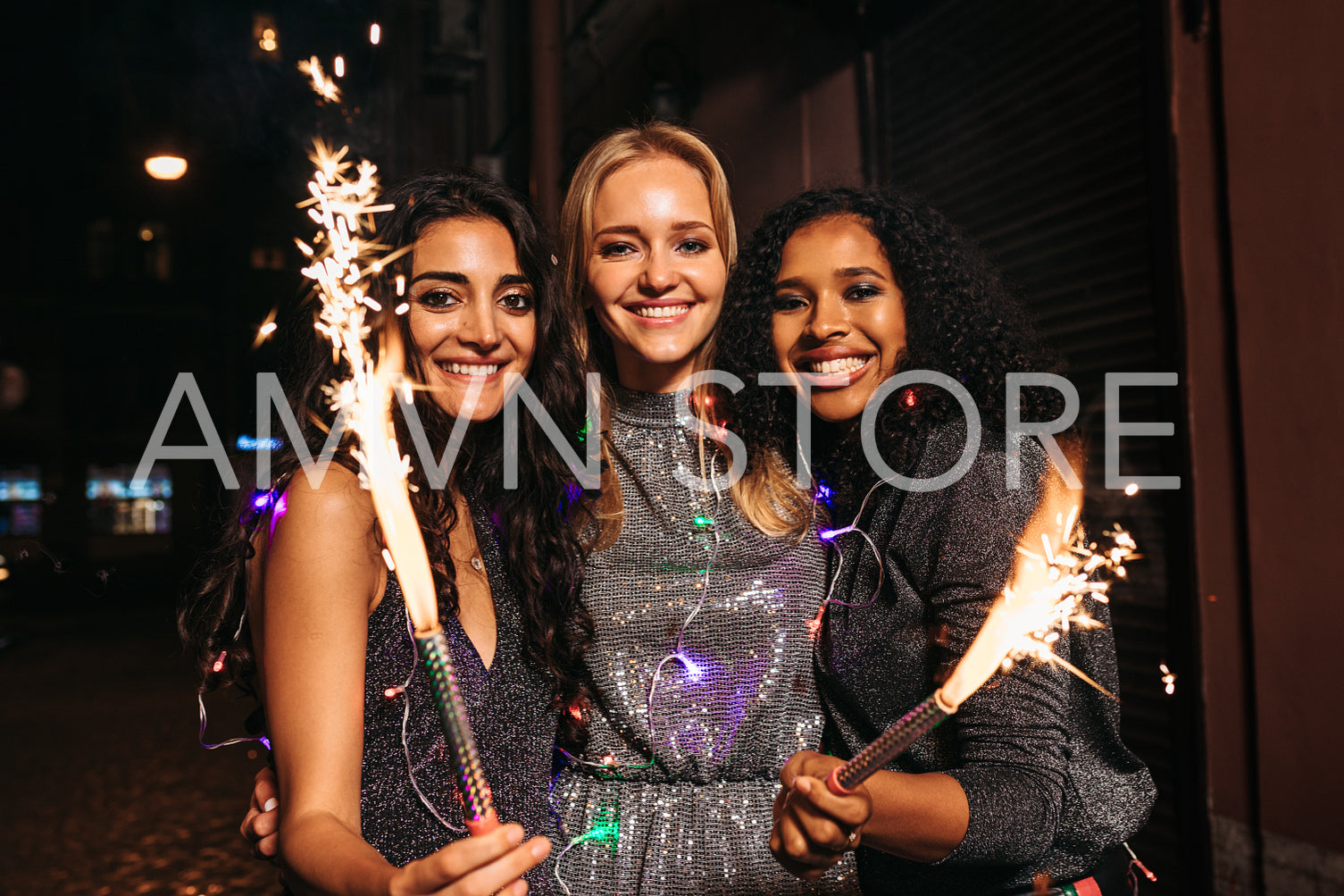 Three young female friends enjoying new years eve with fireworks at night	