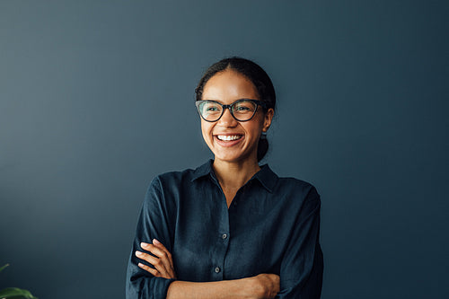 Happy businesswoman with crossed arms standing at home and looking away