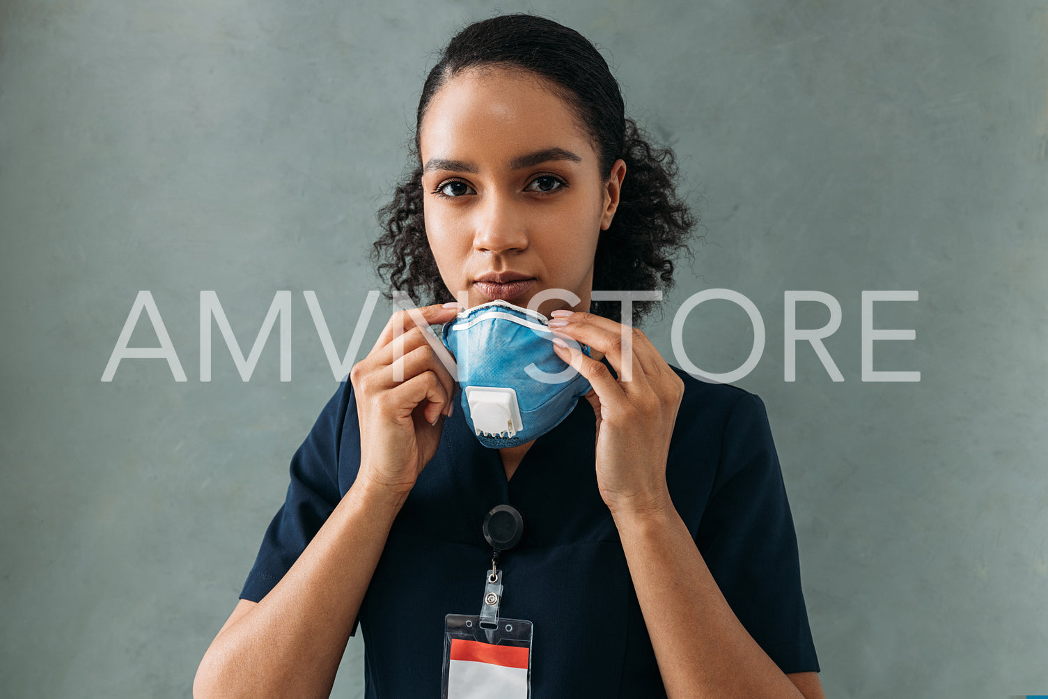 African American nurse holding a protective mask looking at camera at wall	