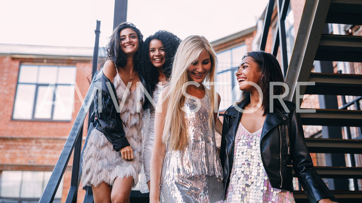 Four young girls go down the stairs. Young friends walking outdoors.	