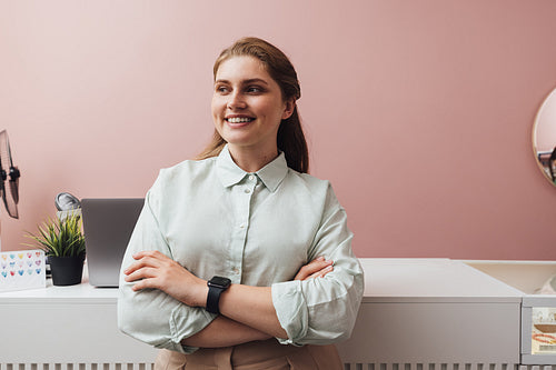 Smiling boutique owner standing at counter with crossed arms loo