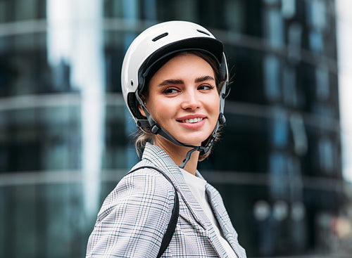 Portrait of a smiling woman wearing cycling helmet standing in front of an office building