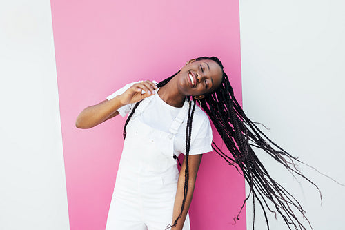 Happy female with long braided hair dancing outdoors at a wall with closed eyes