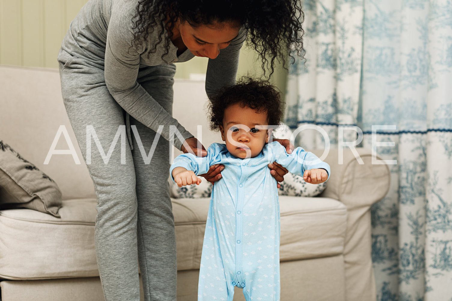 Mother helping little son walking in the room	