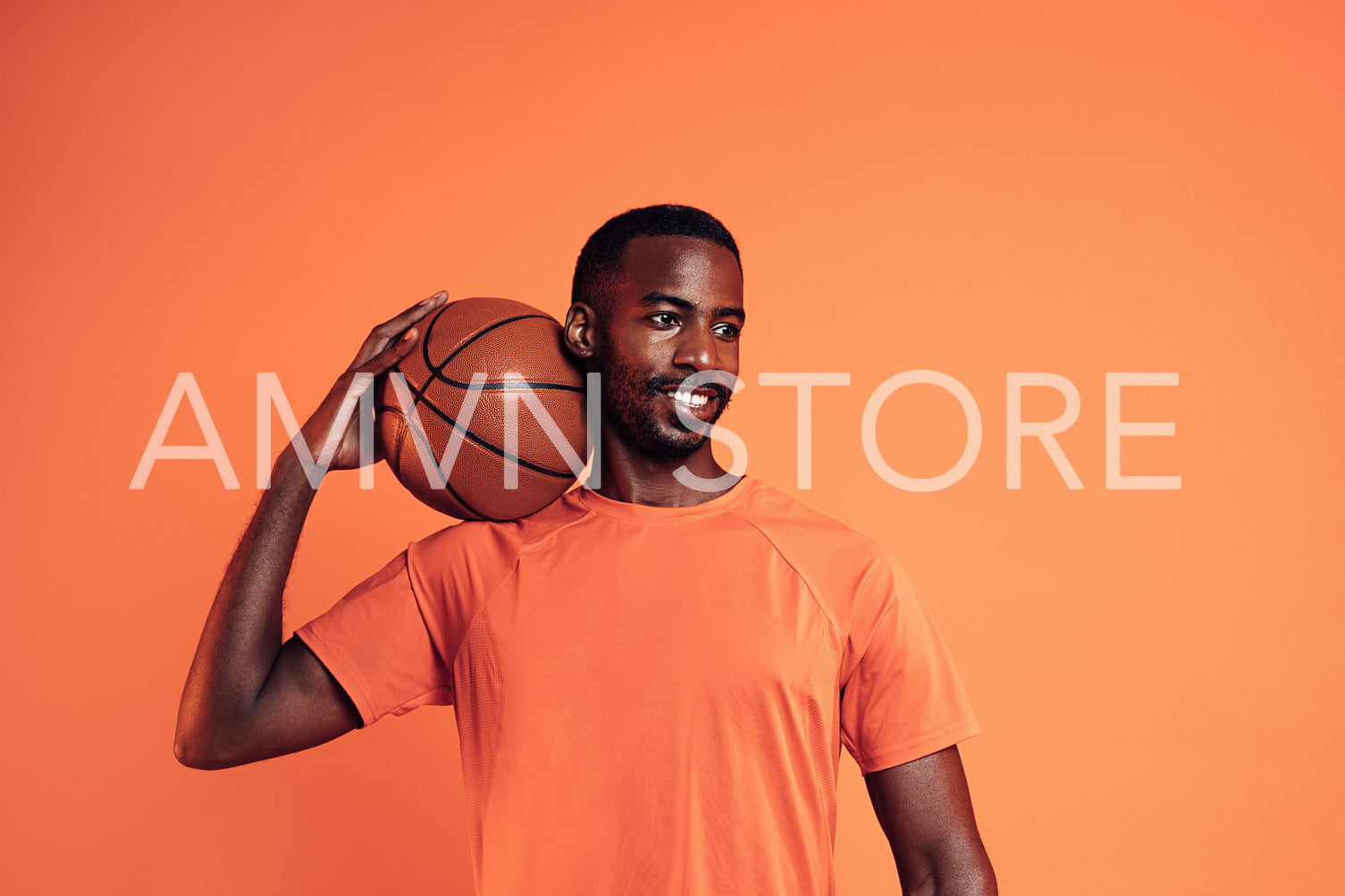 Portrait of a cheerful man wearing an orange t-shirt holding basket ball on his shoulder