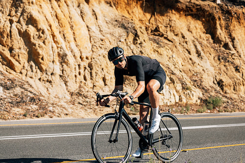 Male rider in helmet and glasses looking at camera while riding his bicycle