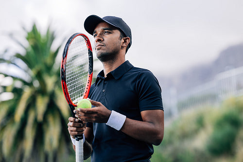 Young tennis player with racket standing outdoors