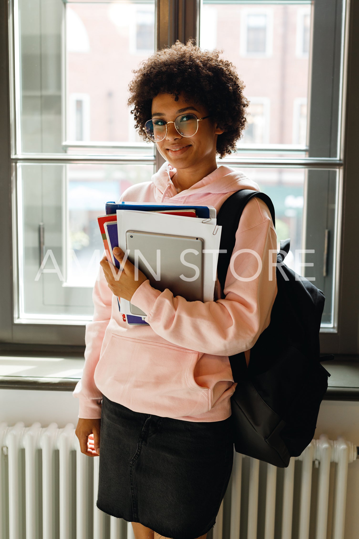 Young smiling student standing at a window, preparing for lecture	