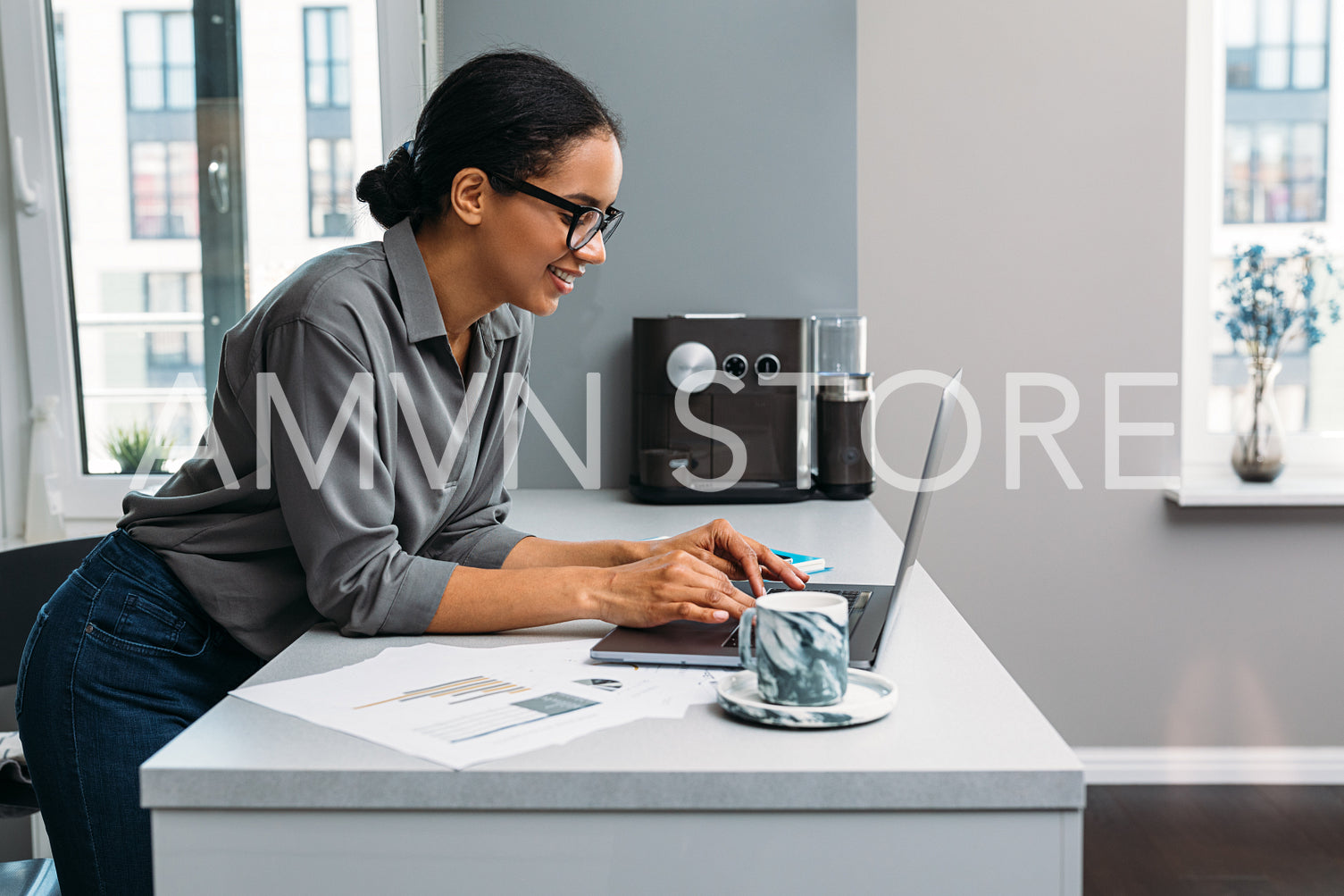 Side view of smiling woman working with laptop on kitchen counter at home	