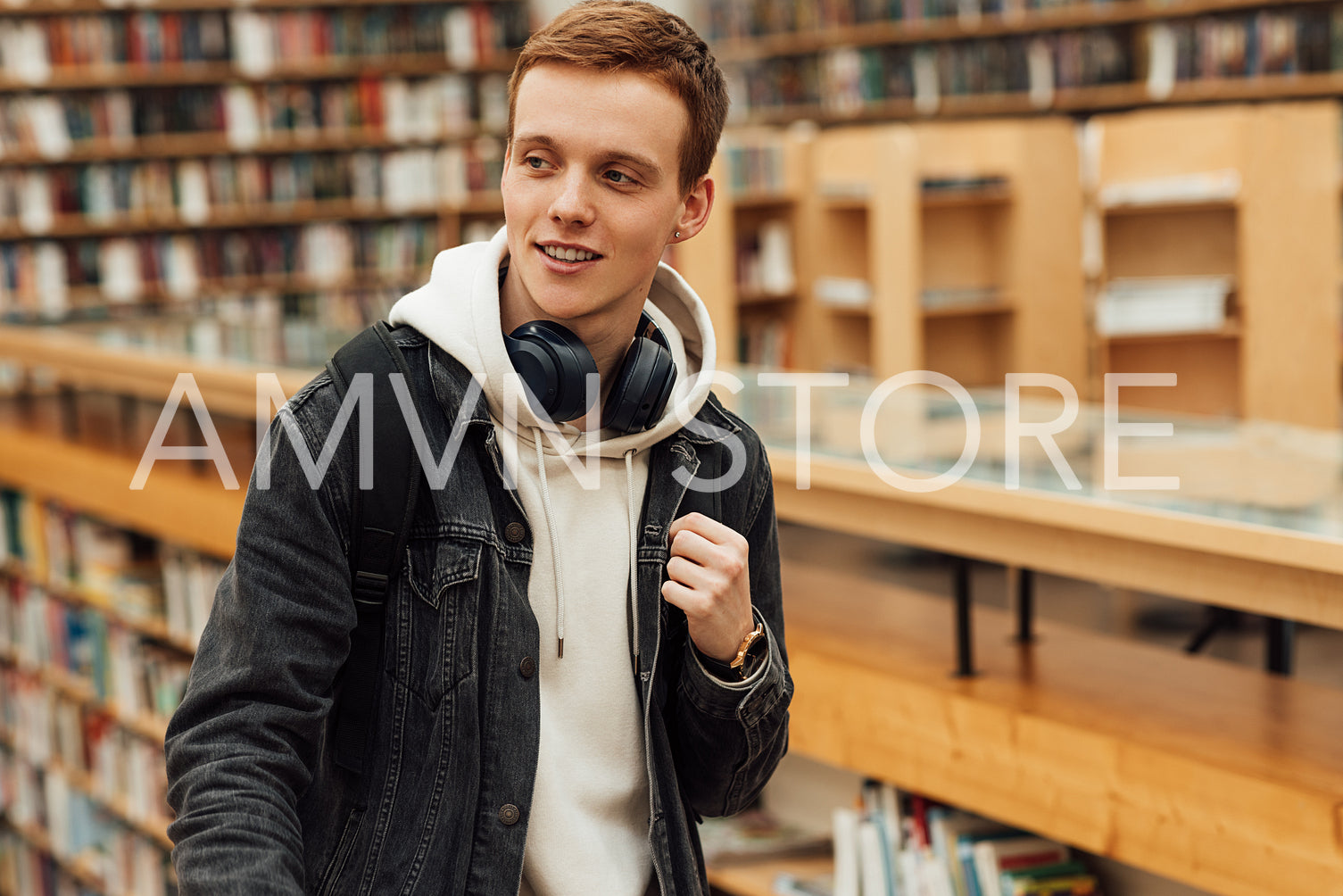 Portrait of a student in casuals standing in library and looking away