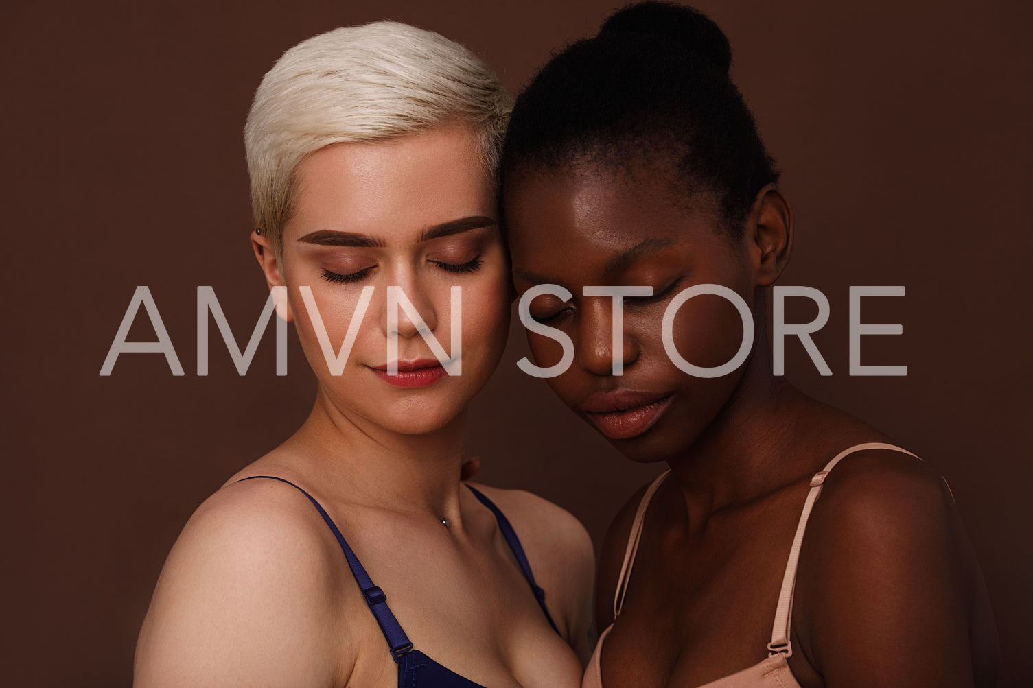 Two young women in lingerie standing with closed eyes head to head