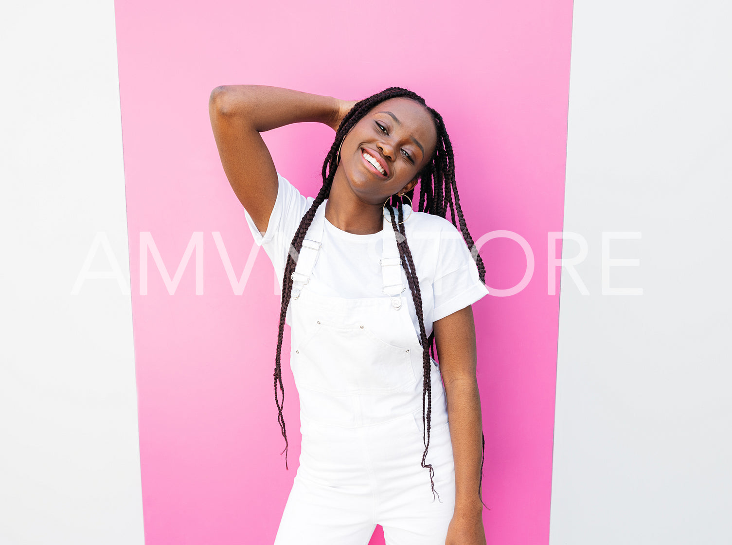 Cheerful girl in a white overall leaning pink stripe on a wall while standing outdoors