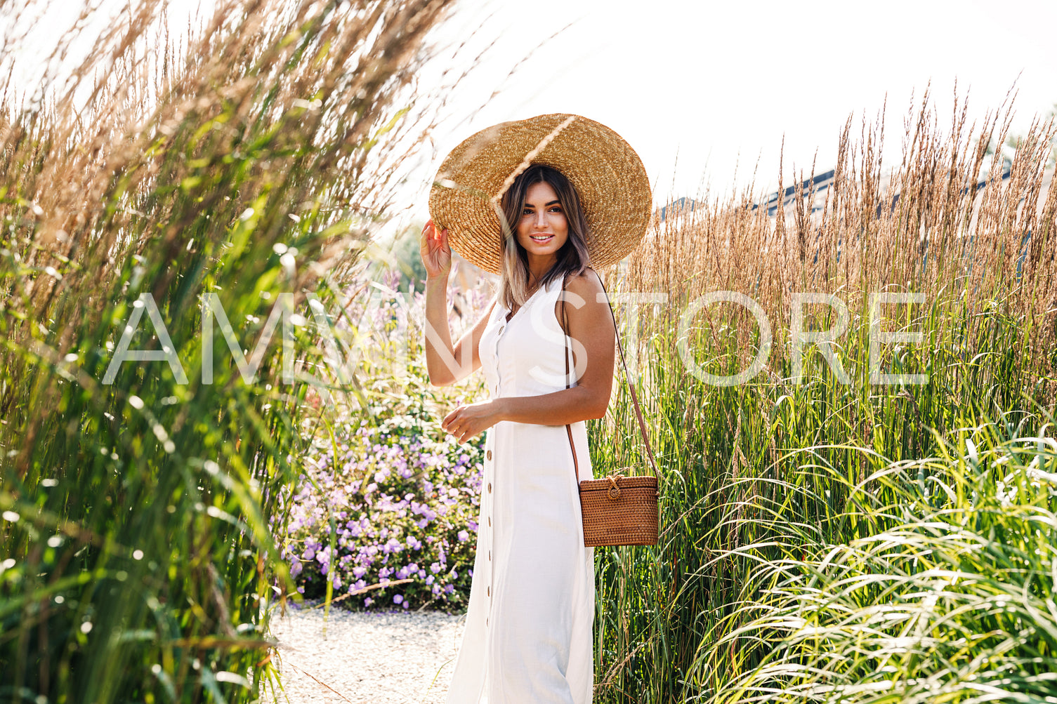 Young stylish woman in a big straw hat standing on the field	