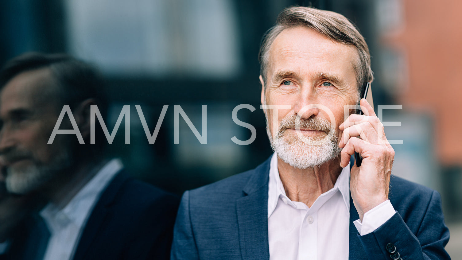 Serious bearded businessman talking on a mobile phone while standing outdoors	