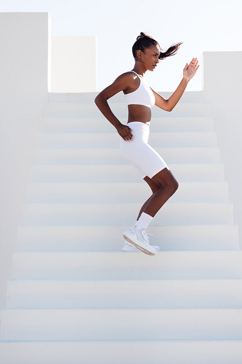 Full length of a slim female stepping down stairs outdoors. Young slim sports woman jogging on stairs.