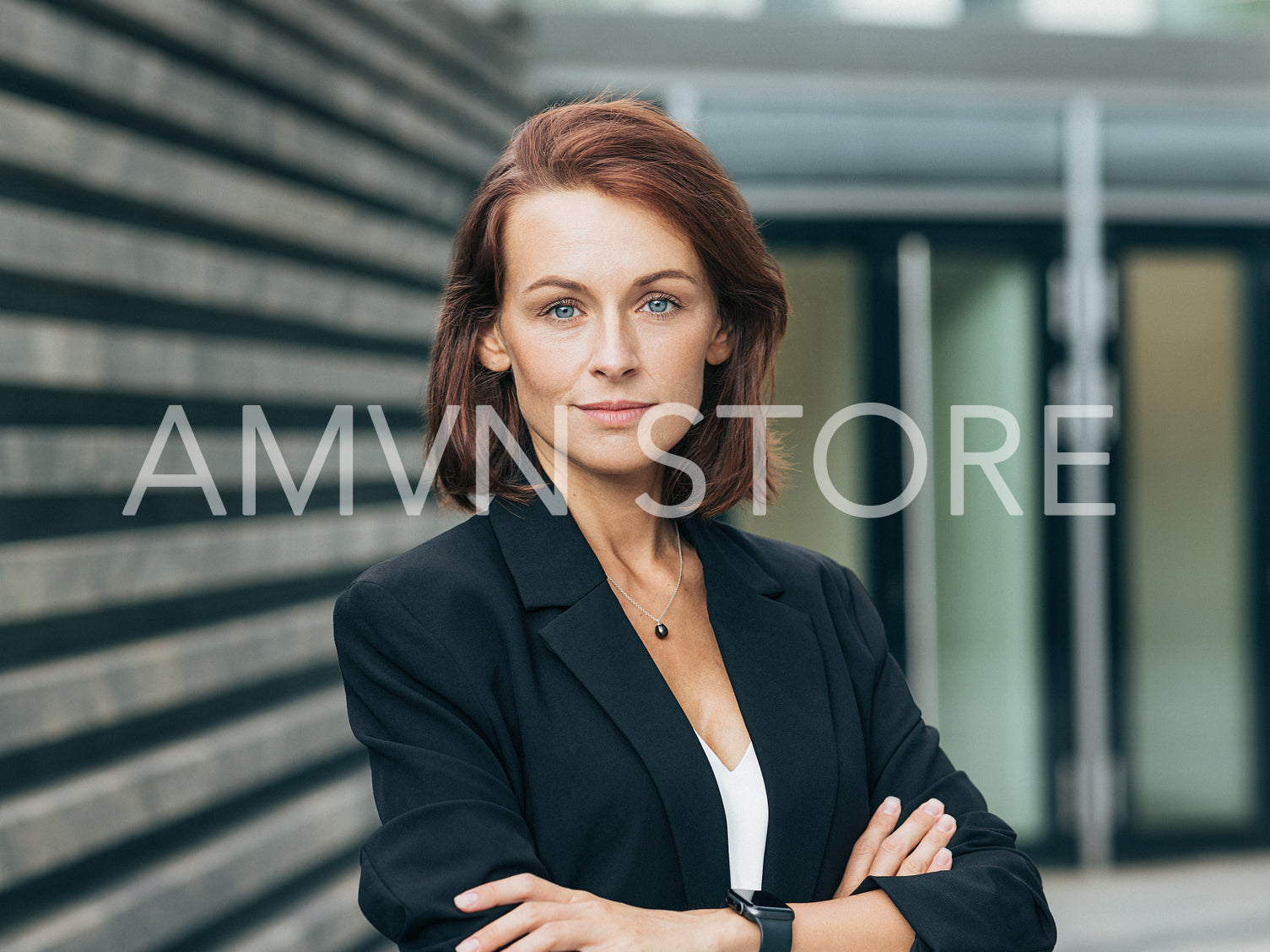 Portrait of a middle-aged female with crossed hands. Businesswoman in black formal clothes with ginger hair.