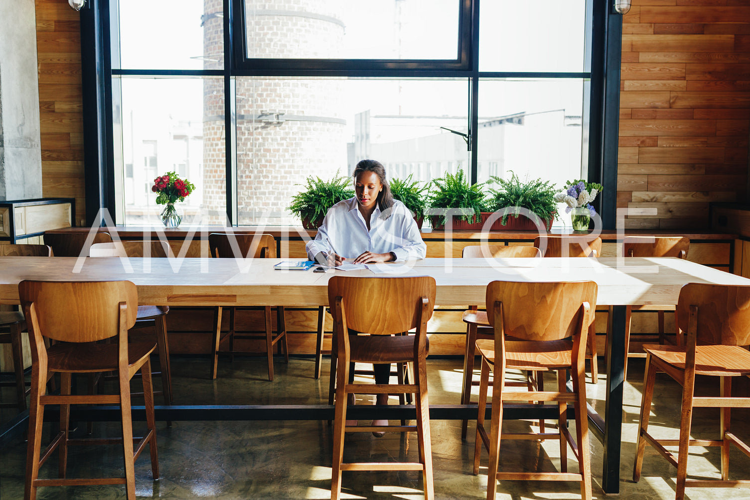 Woman sitting by a desk while reviewing business files in coffee shop	