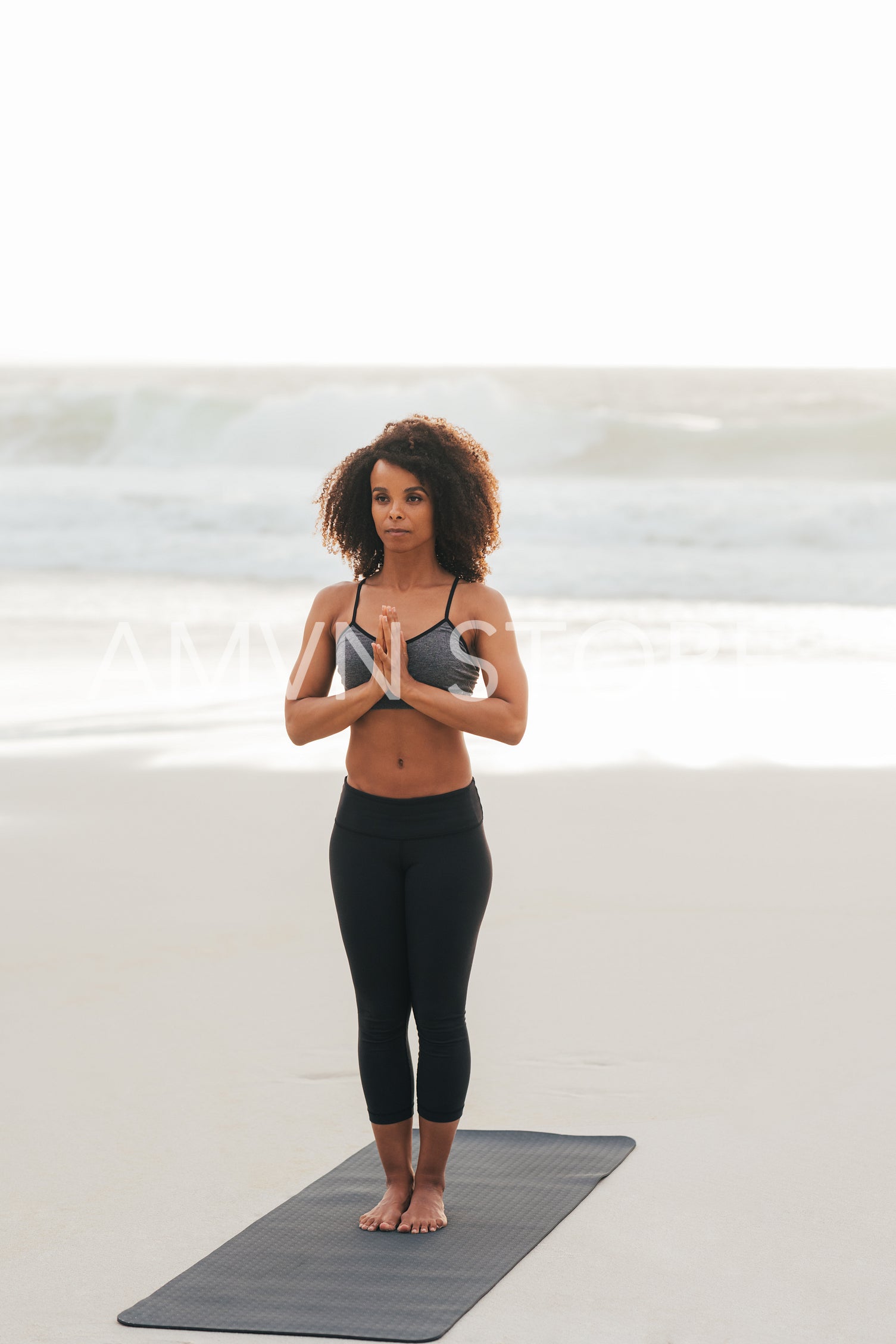 Woman practicing yoga on a beach at sunset