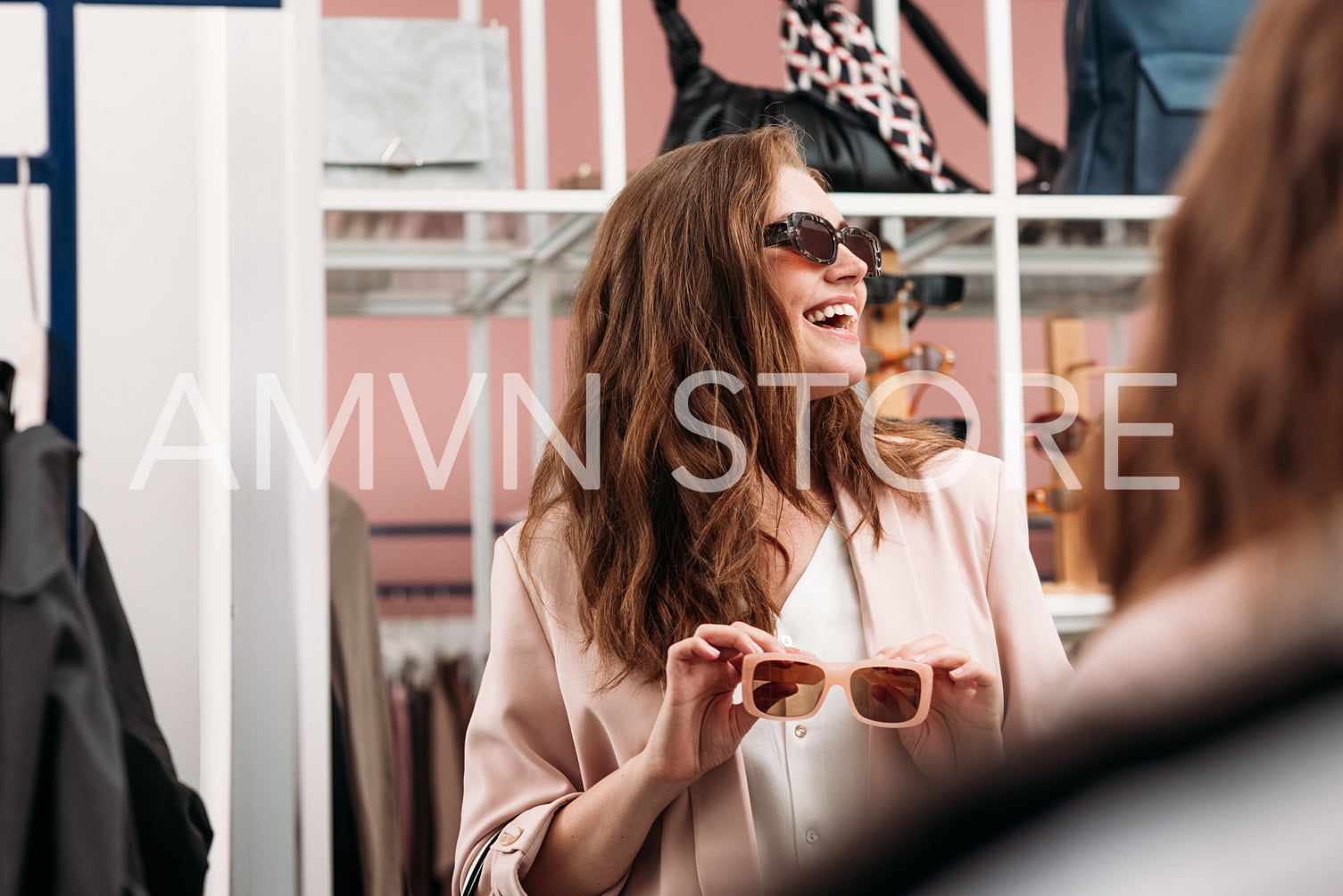 Happy woman looking away while choosing sunglasses in a fashion 