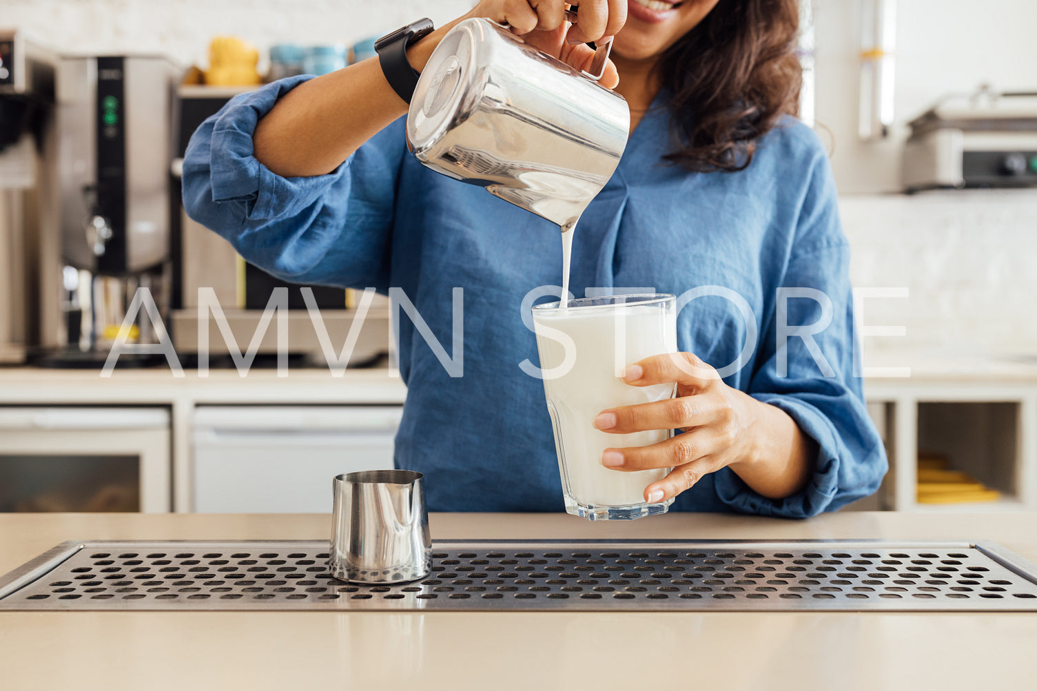 Close up of female barista pouring milk from tamper into a glass	