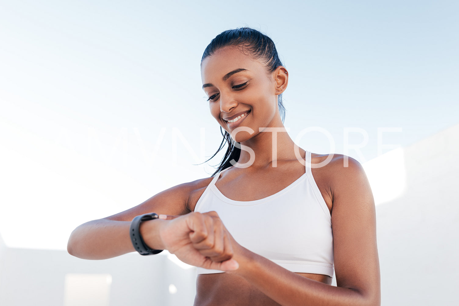 Smiling female in a white fitness bra looking at a smartwatch and checking her heart rate