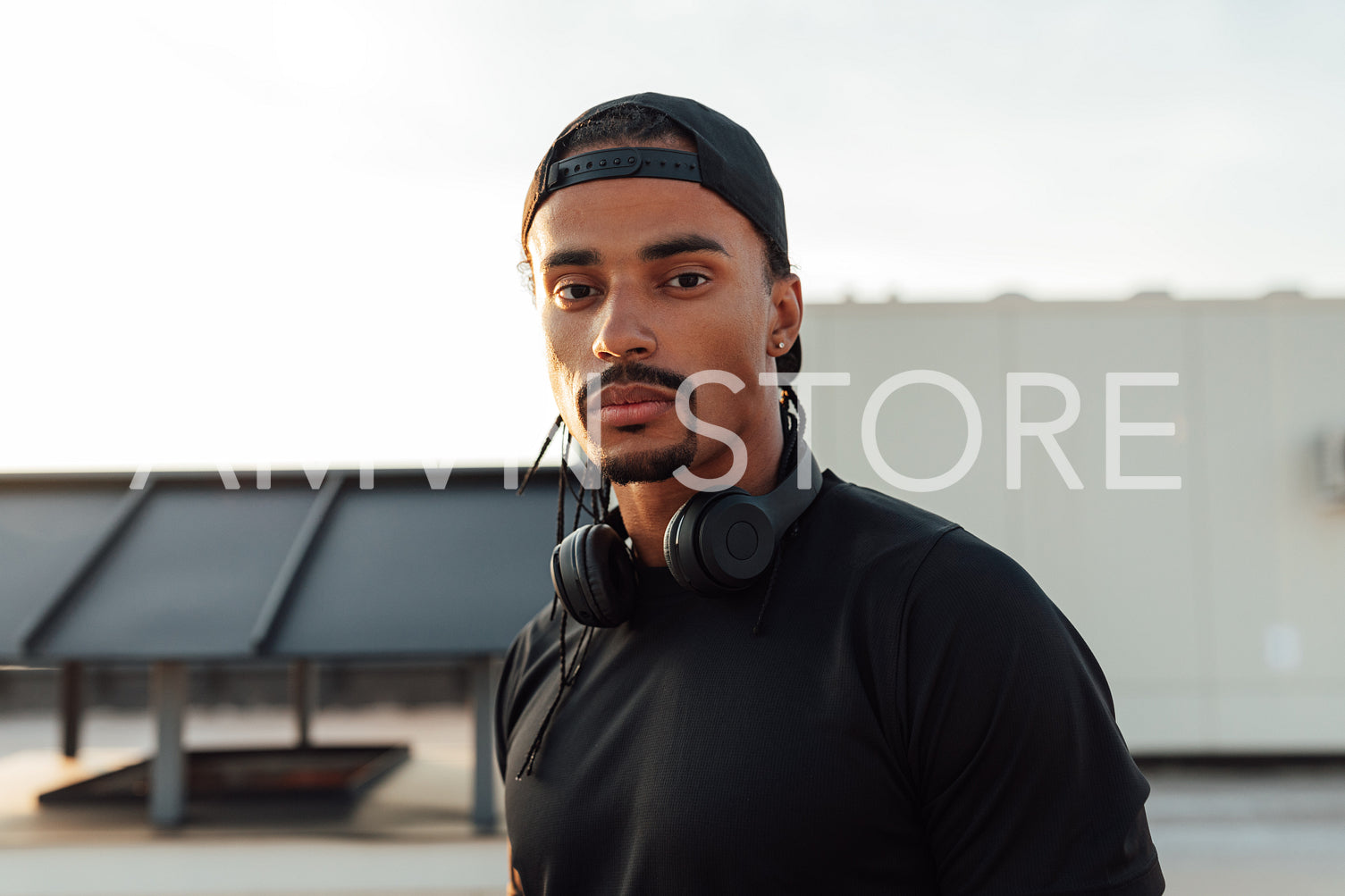 Close-up portrait of a young male athlete wearing a cap and wireless headphones