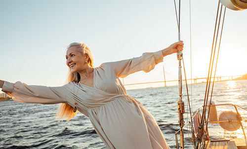 Cheerful mature woman having fun on a private yacht at sunset