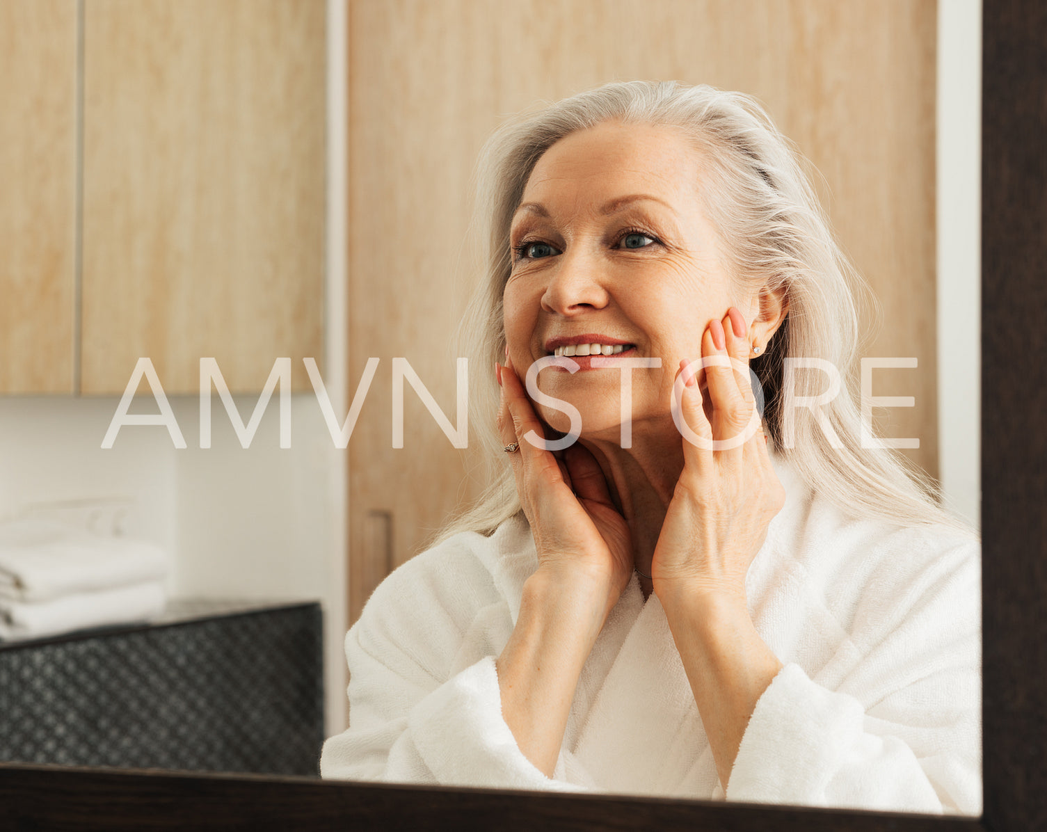 Woman with grey hair examines her face