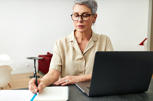 Mature woman writing on a note pad