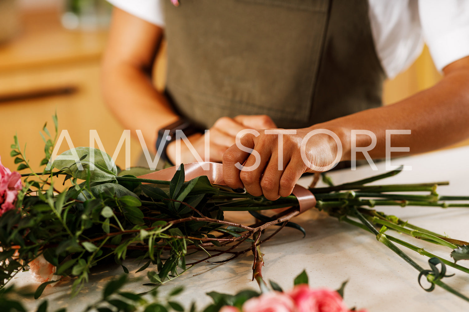 Hands of a female florist placing the stalks of a bouquet of flowers	