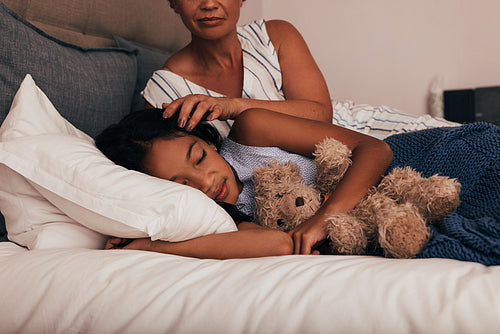 Mature woman adjusting the hair of her granddaughter while she sleeping