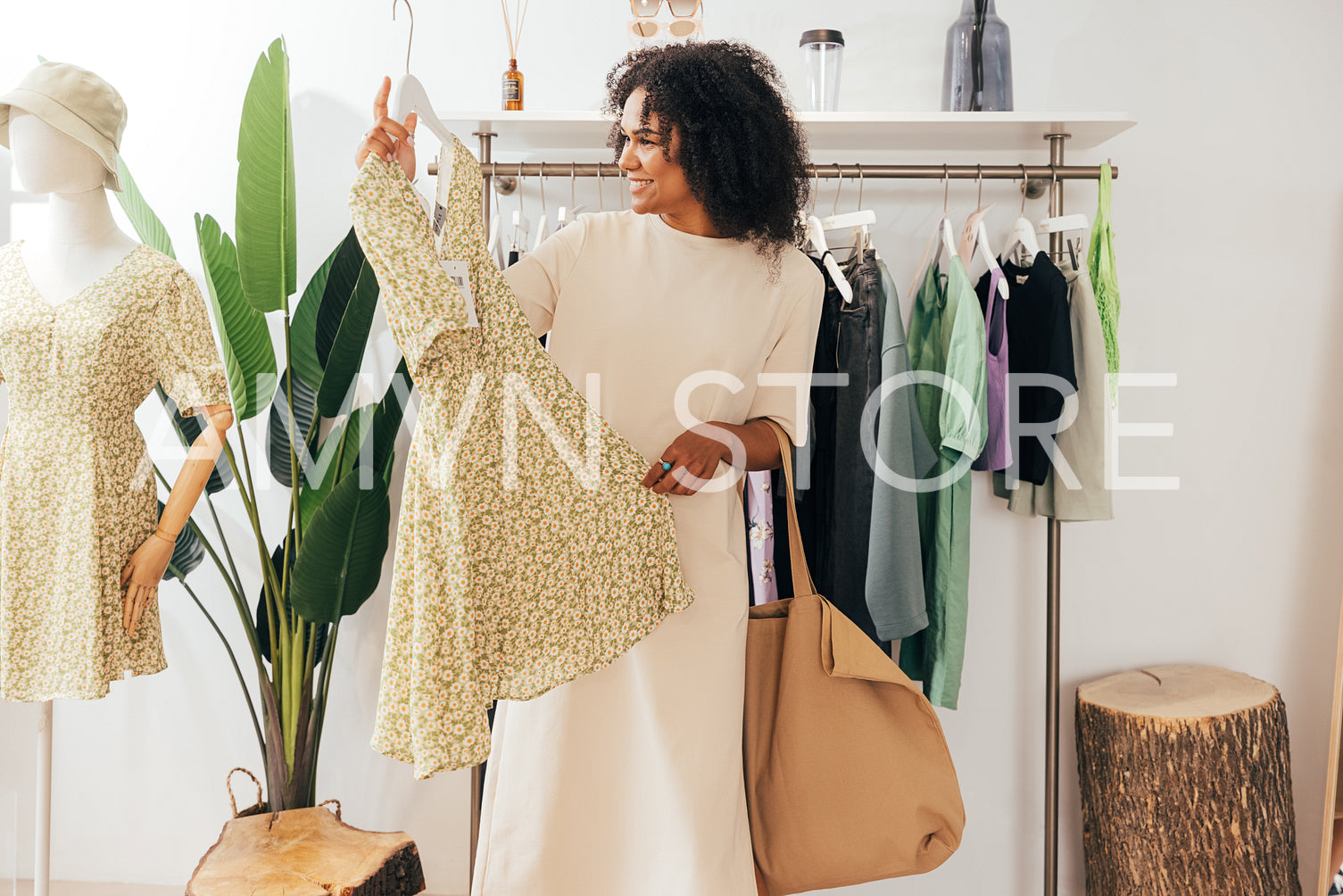 Fashionable woman standing with dress in small boutique