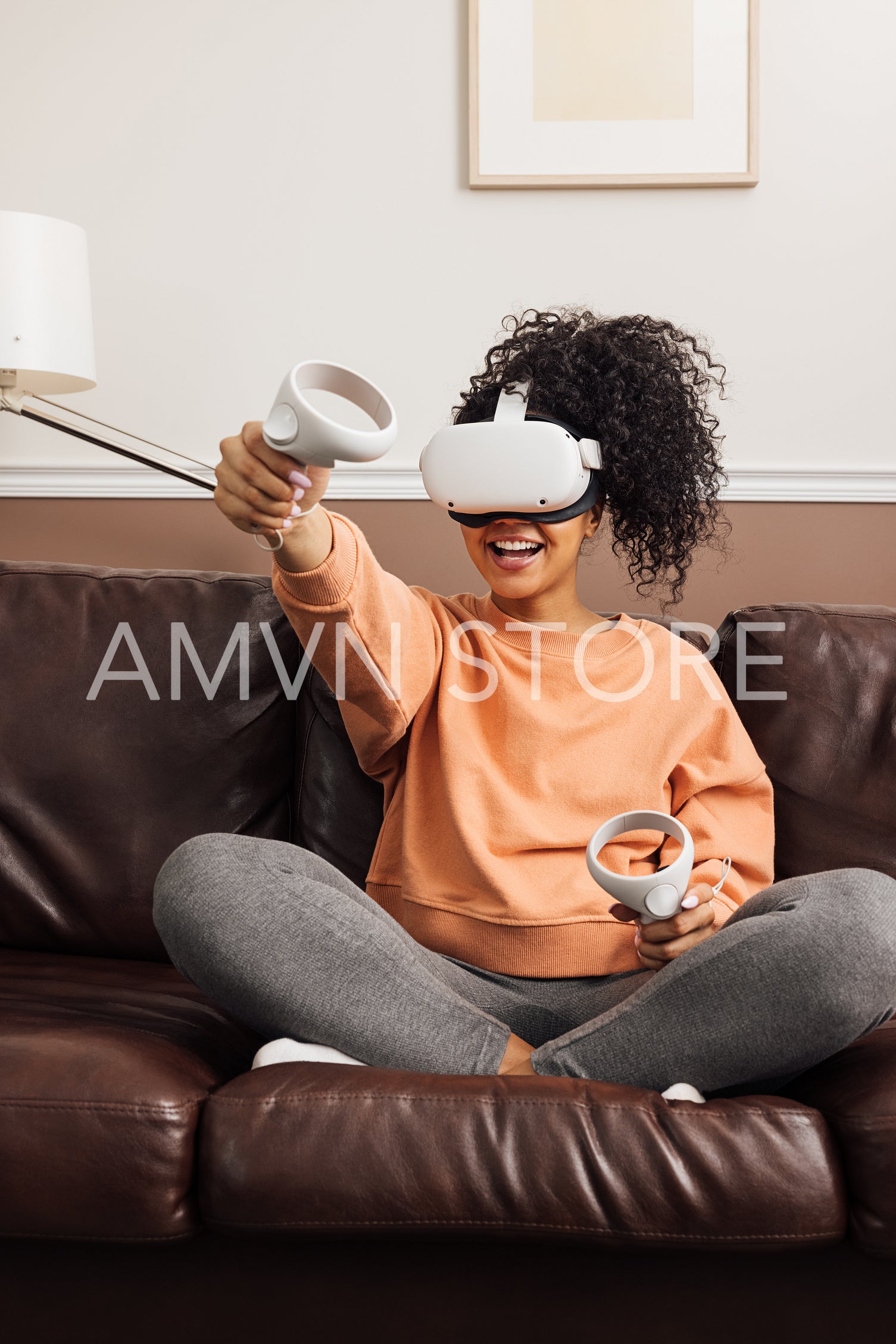 Woman with joysticks and VR goggles playing video games on a sofa	