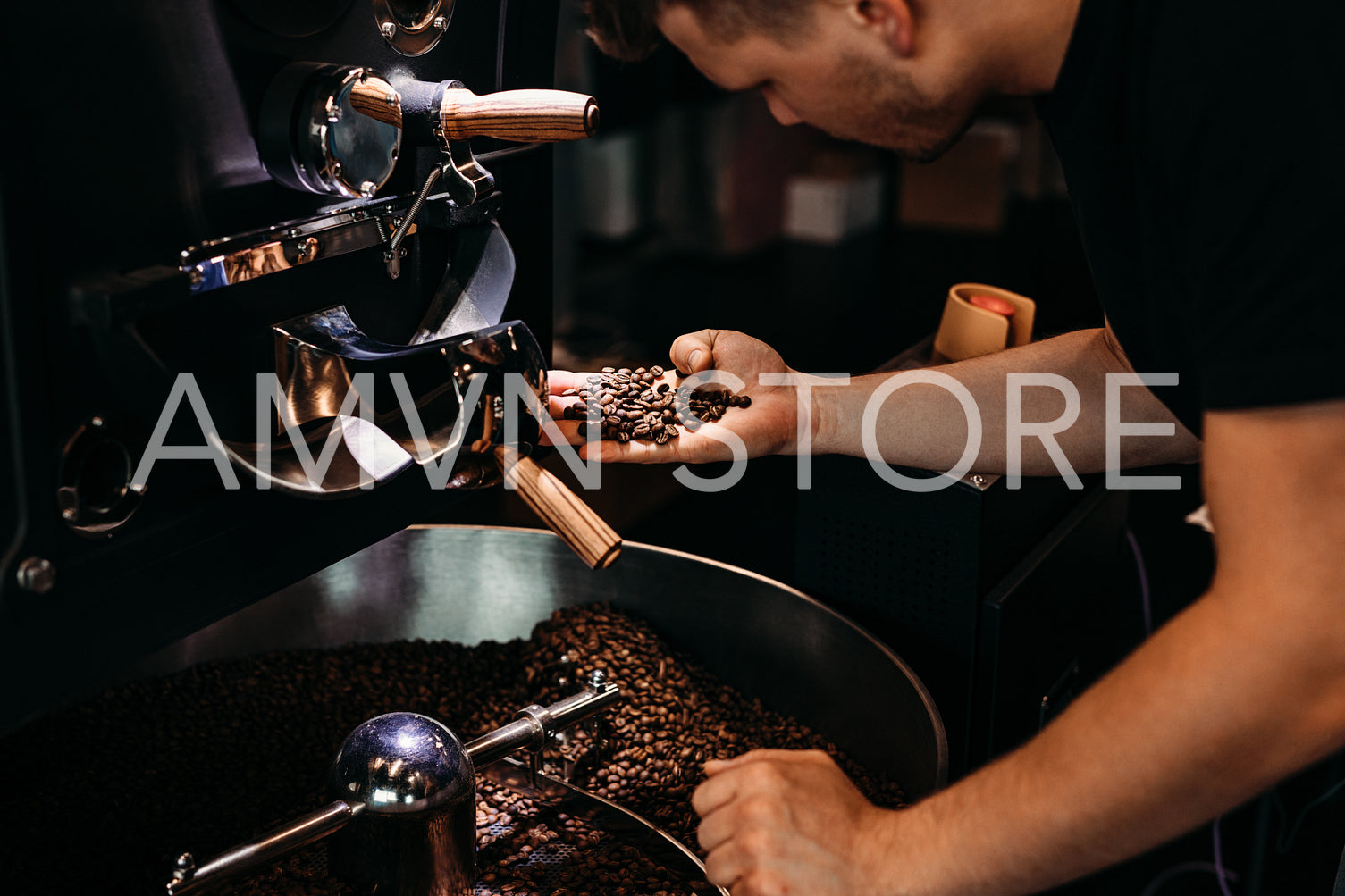 Man working at coffee production. Barista controling coffee grounds roasting process.	