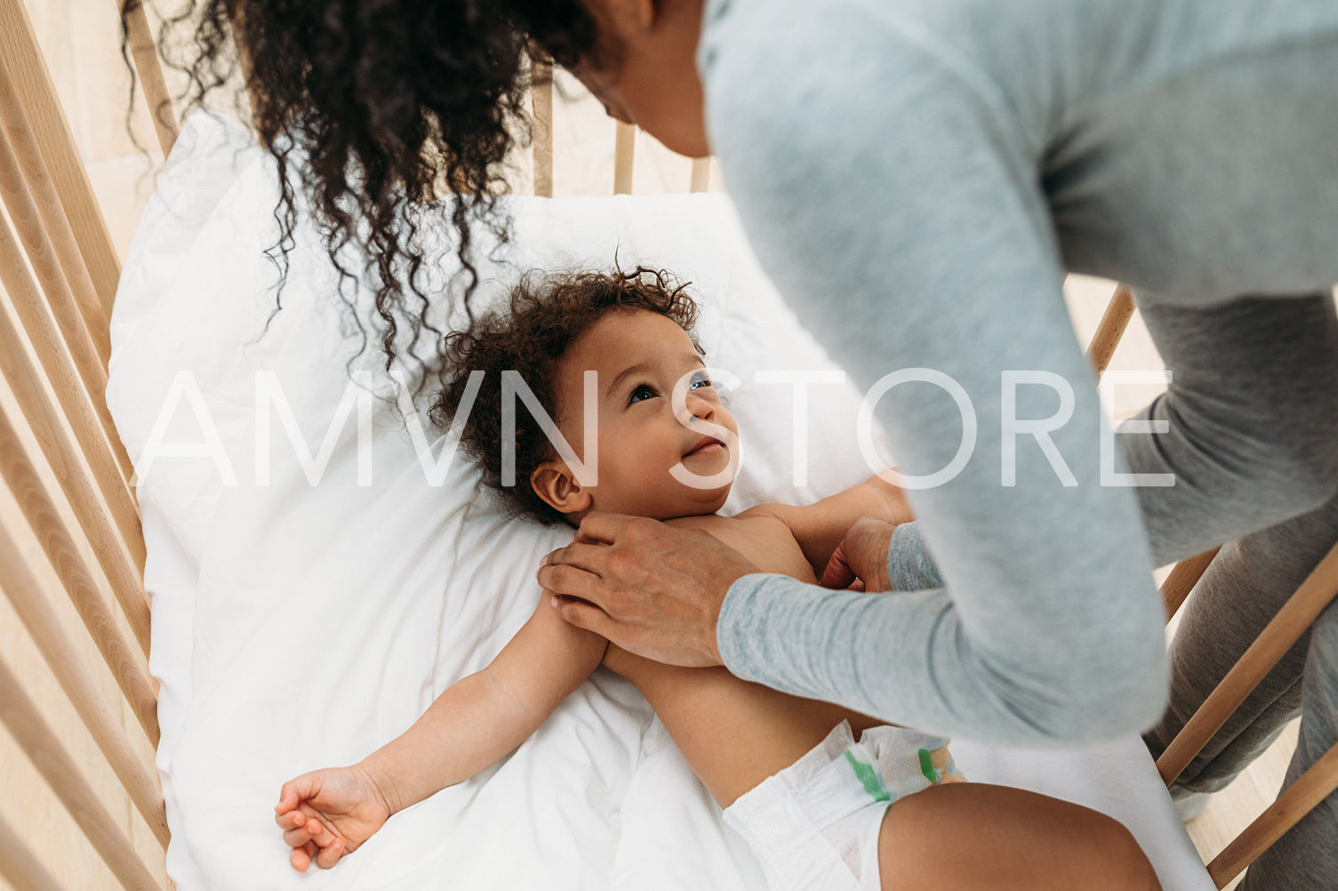 Mother putting her newborn baby boy into crib	